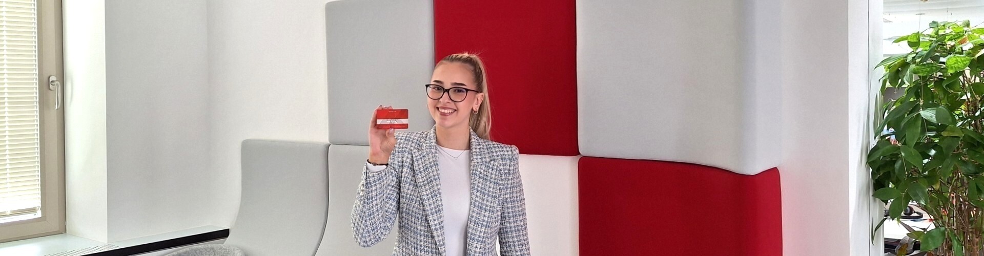 Junge Frau lächelt mit Ihrer AktivKarte in der Hand in die Kamera